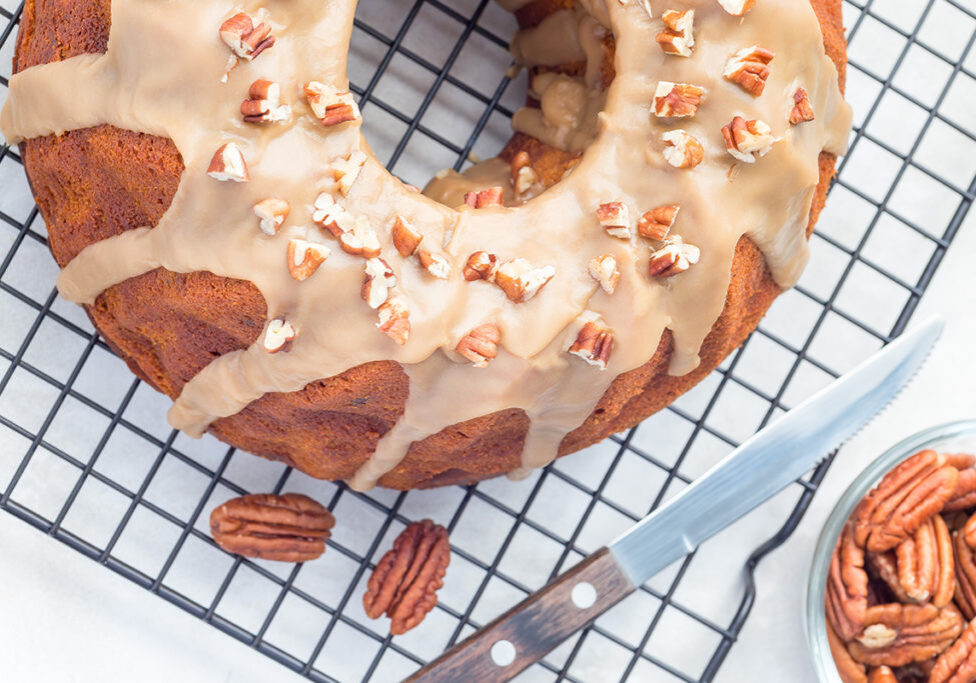 Sweet potato and pecan nuts pound cake with caramel icing on a cooling rack, vertical,  top view